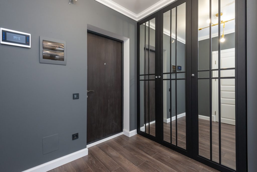 Interior of corridor of modern apartment with wooden doors and parquet floor and mirrored wardrobe